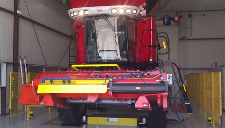 A red combine is sitting in a warehouse.