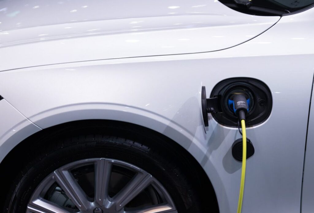 A white car is plugged into an electric charger.